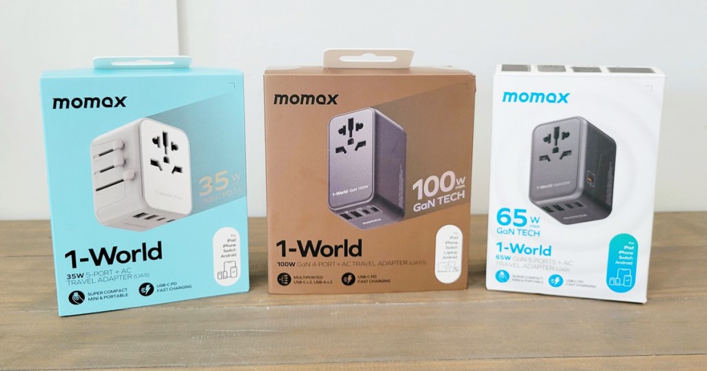 three boxes of MOMAX Universal Travel Adapters on wood table