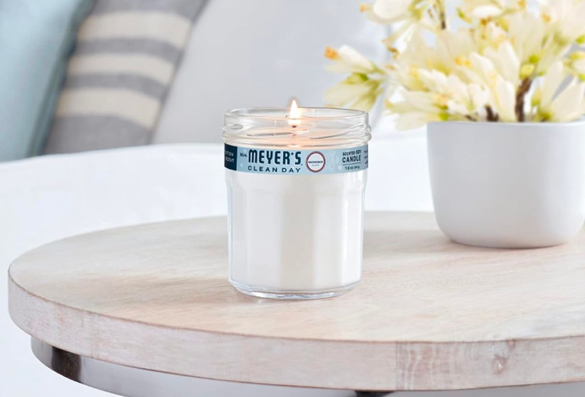 Mrs Meyers Soy Aromatherapy Candle in Snowdrop scent on a table next to a sofa