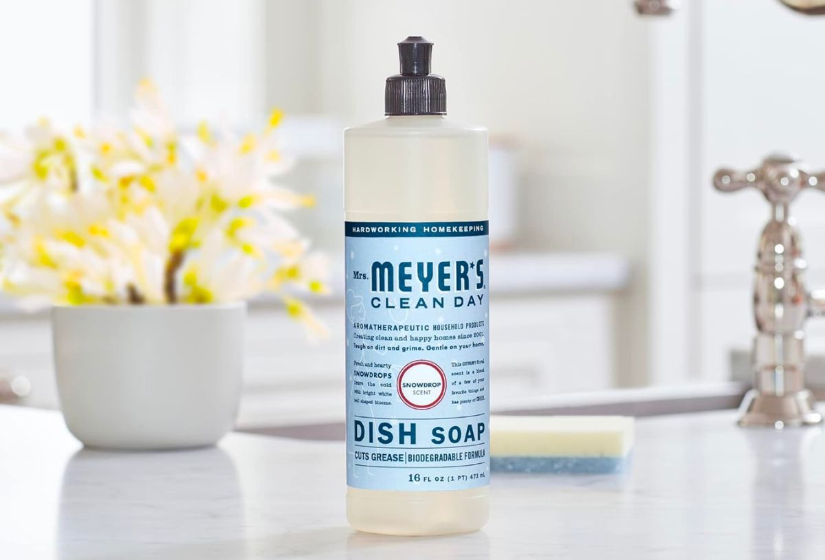 a bottle of Mrs. Meyers Liquid Dish Soap in Snowdrop scent sitting on a table next to a sofa 