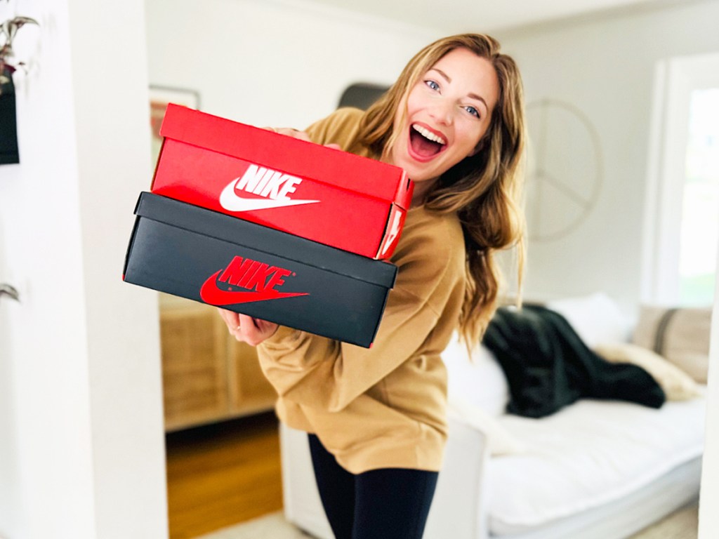 woman holding a stack of nike shoe boxes