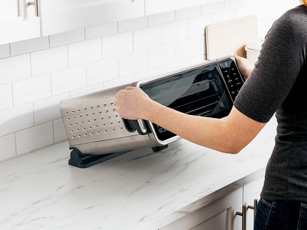 woman flipping up a ninja foodi oven to save space on counter