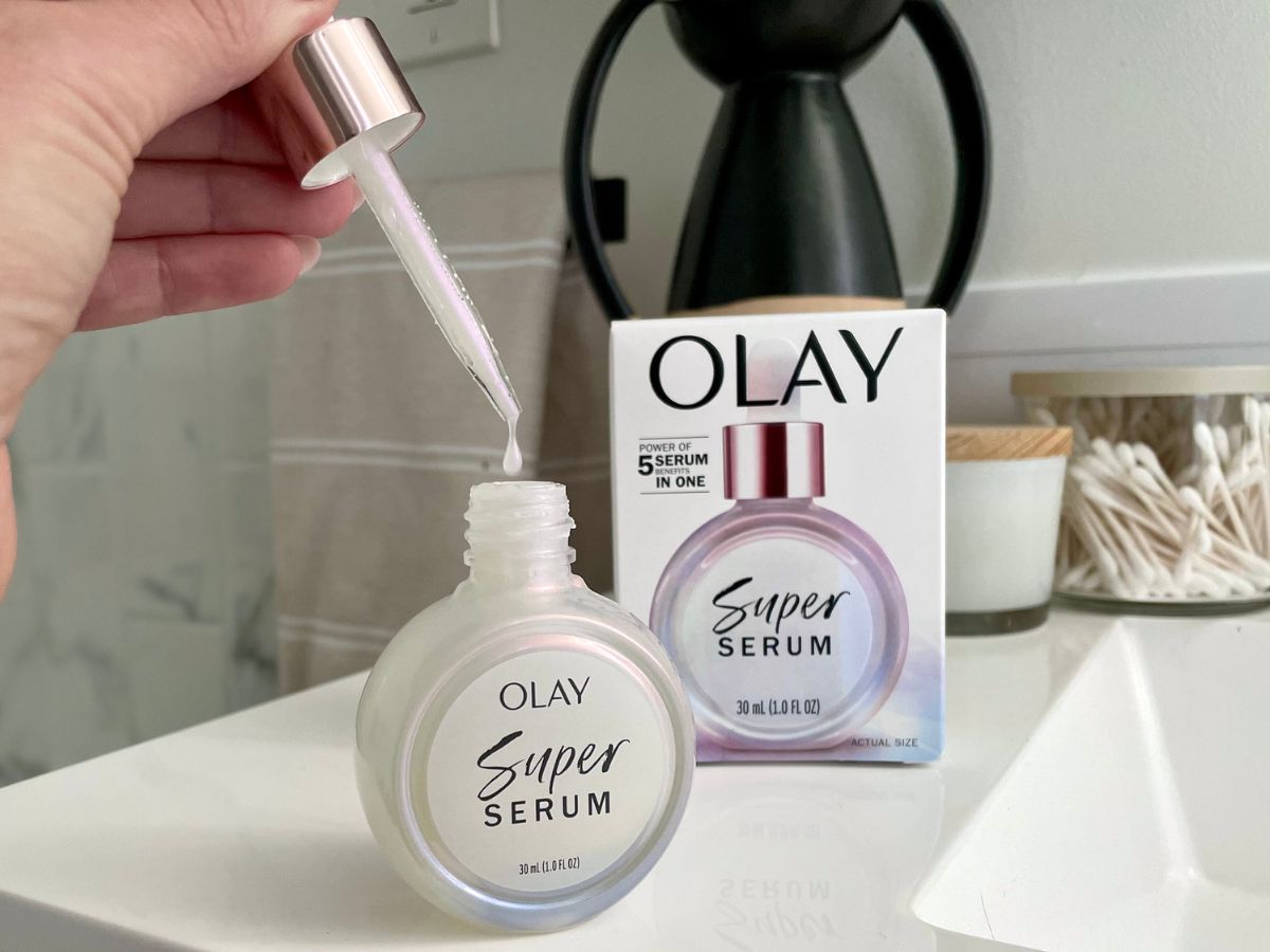 Hand holding the dropper and dispensing a drop of Olay Super Srum back into the bottle