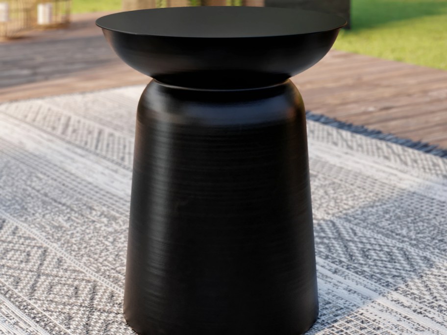 black plant stand on outdoor area rug