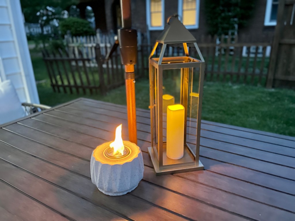 A candle and outdoor lantern displayed on a patio table at night