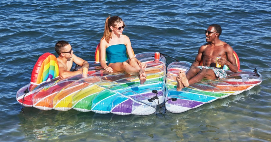 people hanging out 3 rainbow pool floats tied together