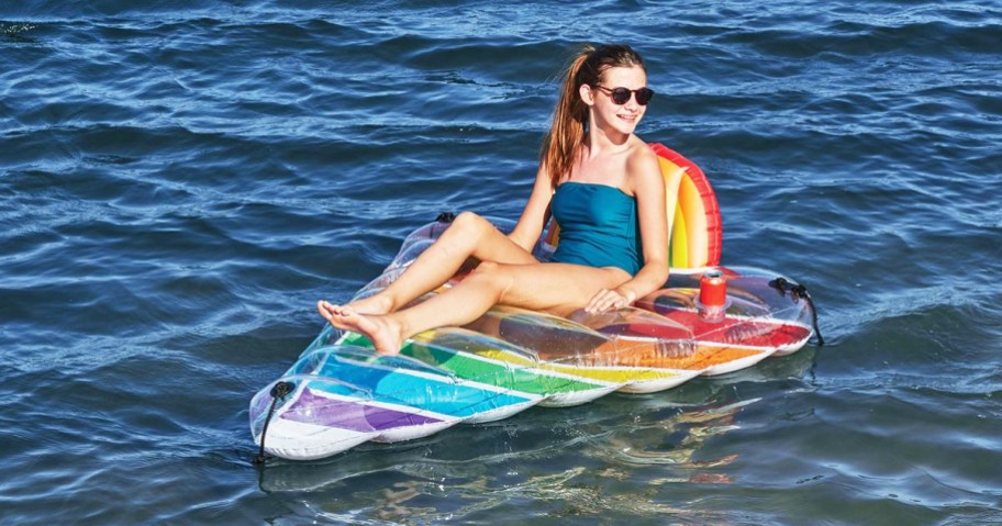 woman floating on a triangular rainbow pool float