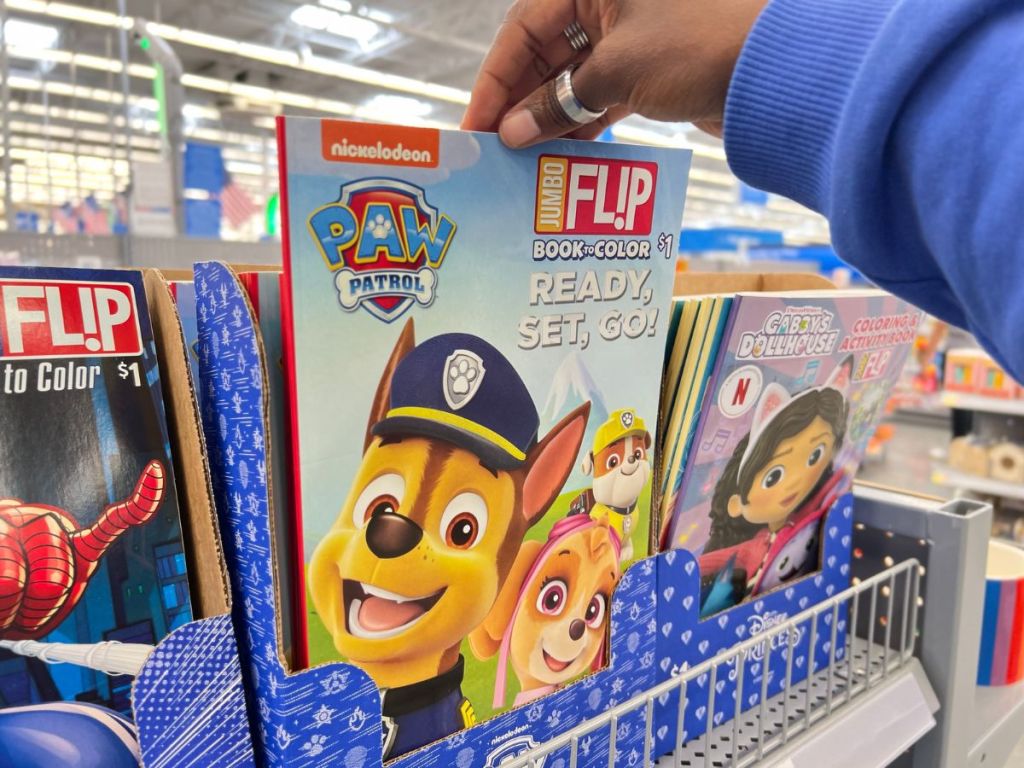 A womans hand grabbing a Paw patrol activity book from the store shelf