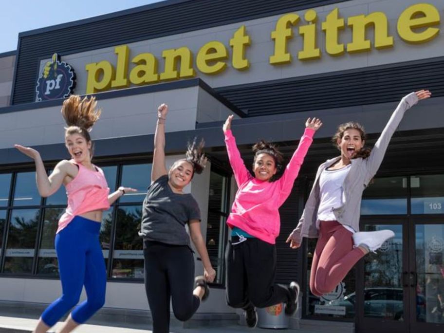 Four girls jumping up in front of a Planet Fitness