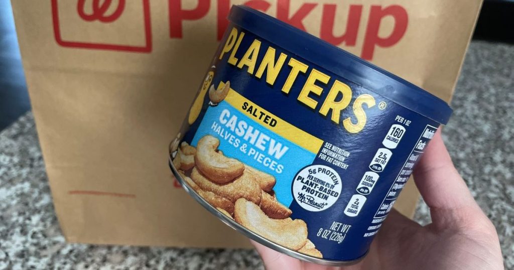 Hand holding a can of Planters cashews