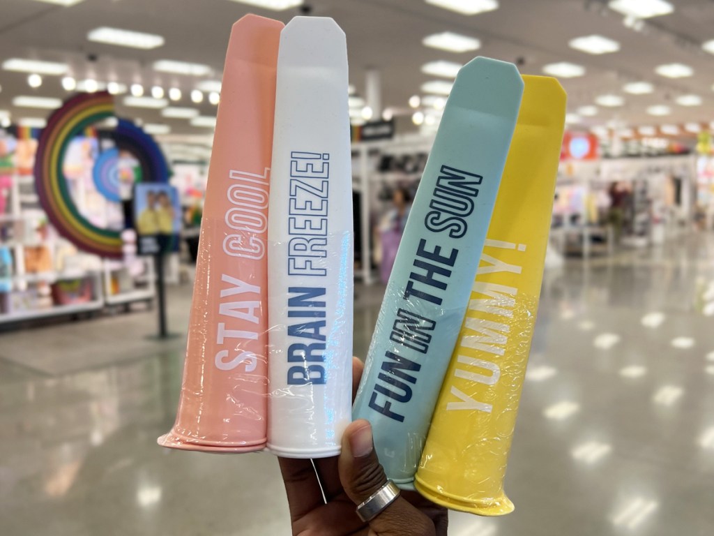 hand holding up sets of popsicle molds with fun sayings on them