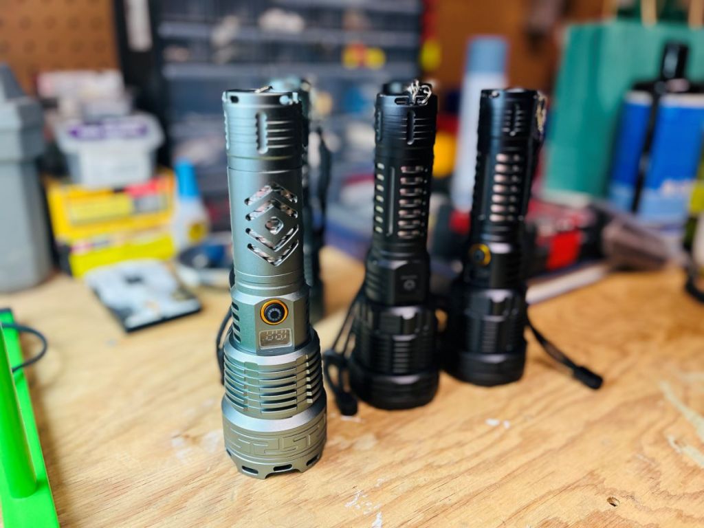 Three rechargeable flashlights sitting on a workbench