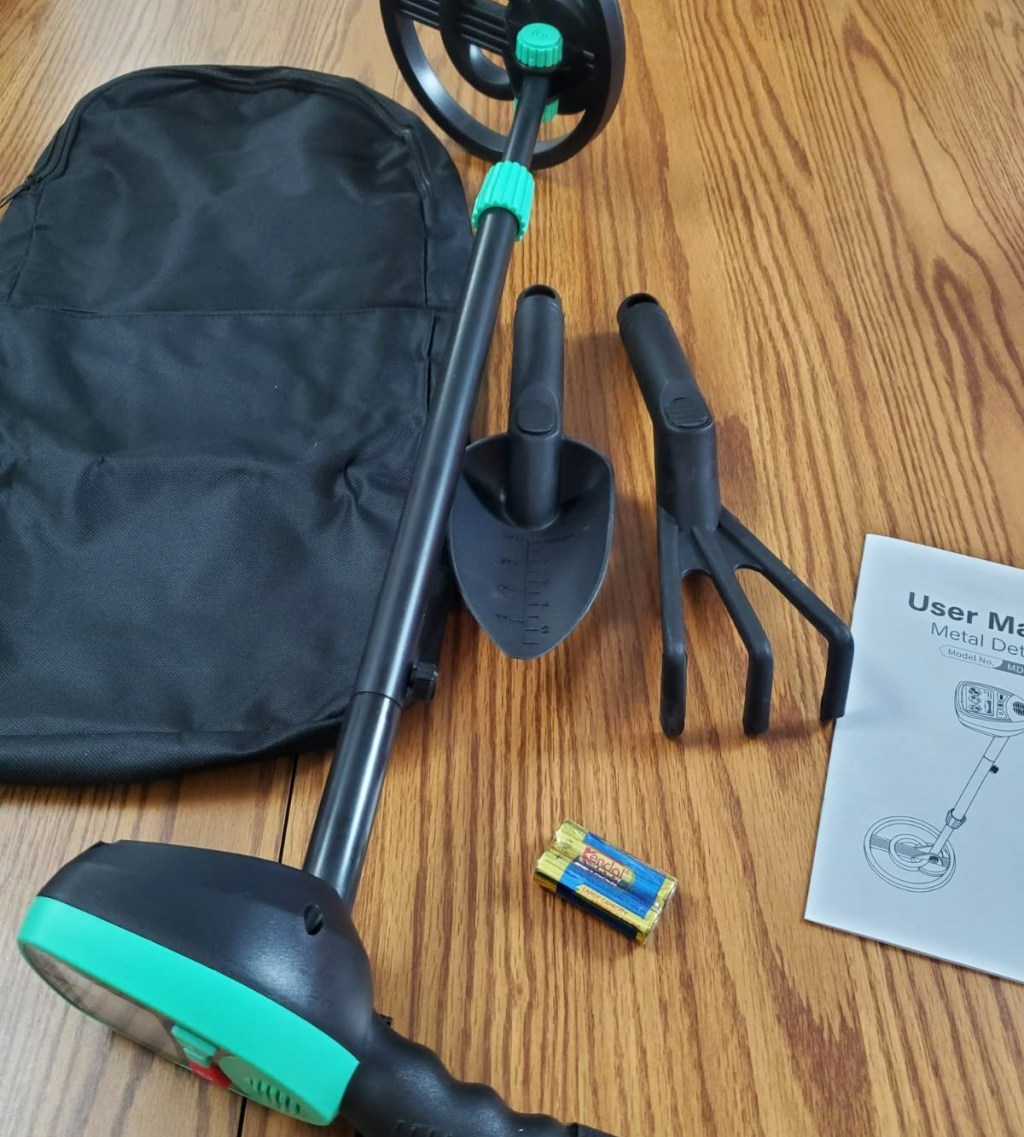 green and black metal detector, backpack, and shovel on wood table