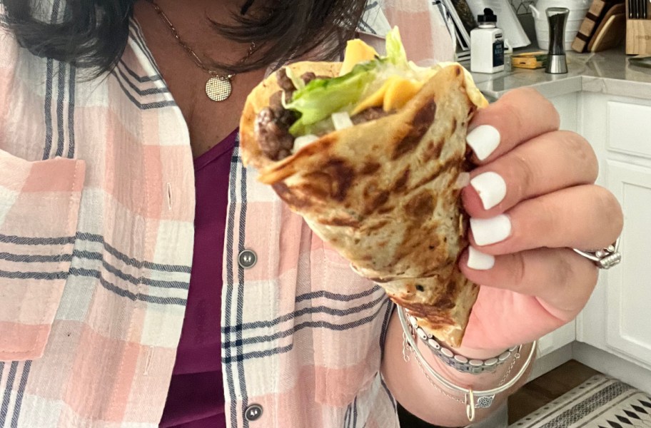 hand holding a smash burger taco made on a blackstone griddle