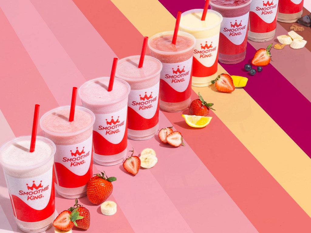 smoothie king smoothies in a row with fruit in front of them
