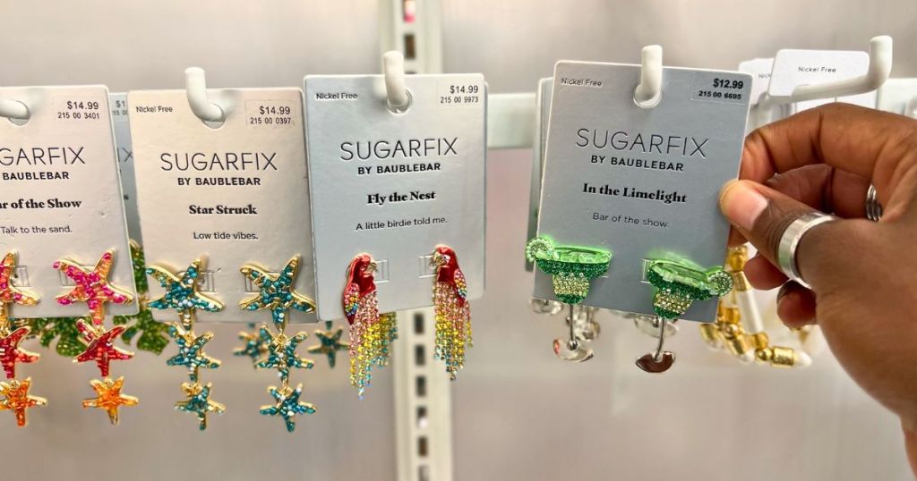 a woman's hand holding a pair of earrings on a card from the Sugarfix jewelry collection at target