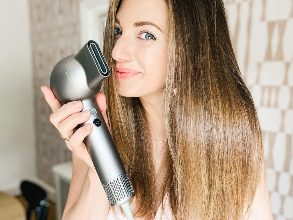 woman holding up a silver hair dryer