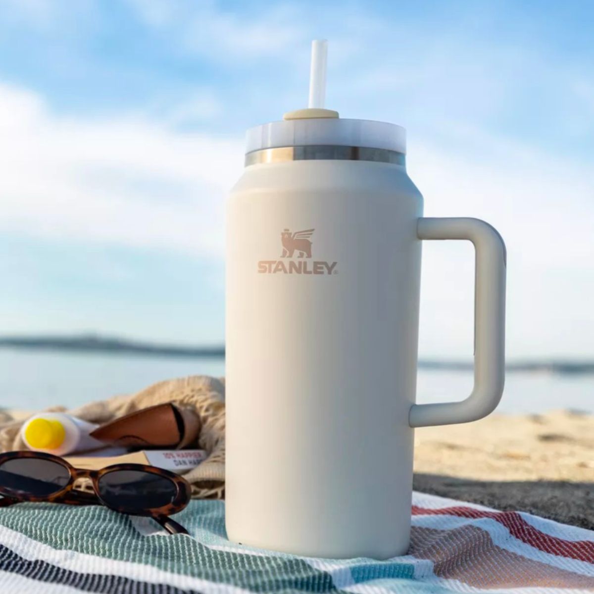 THE QUENCHER H2.0 FLOWSTATE tumbler sitting on a blanket at the beach