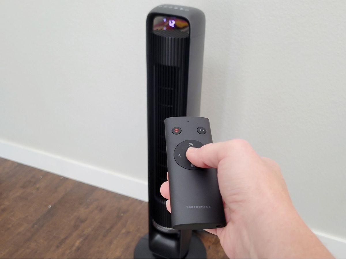 hand using a remote to operate a Taotronics Tower Fan 