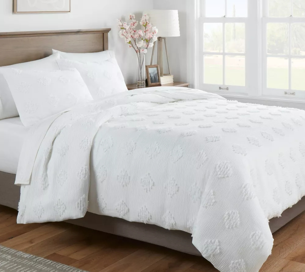 Bed with white comforter and pillows on it