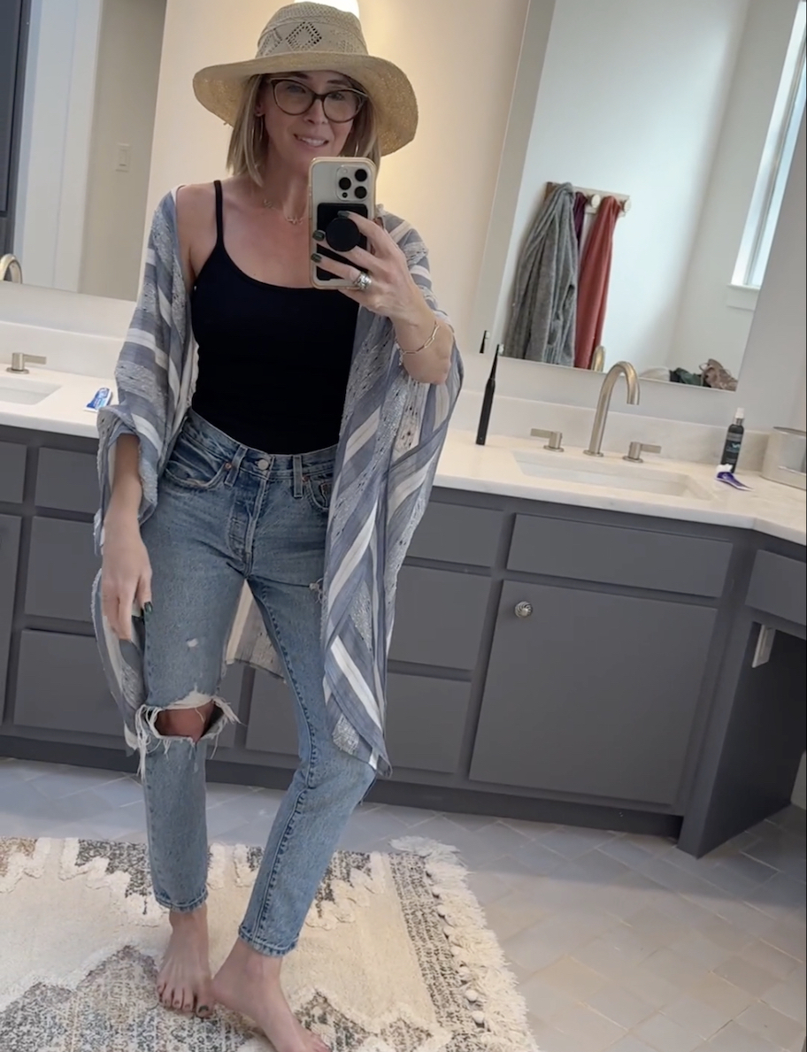 woman taking selfie in mirror wearing jeans cover up and floppy hat