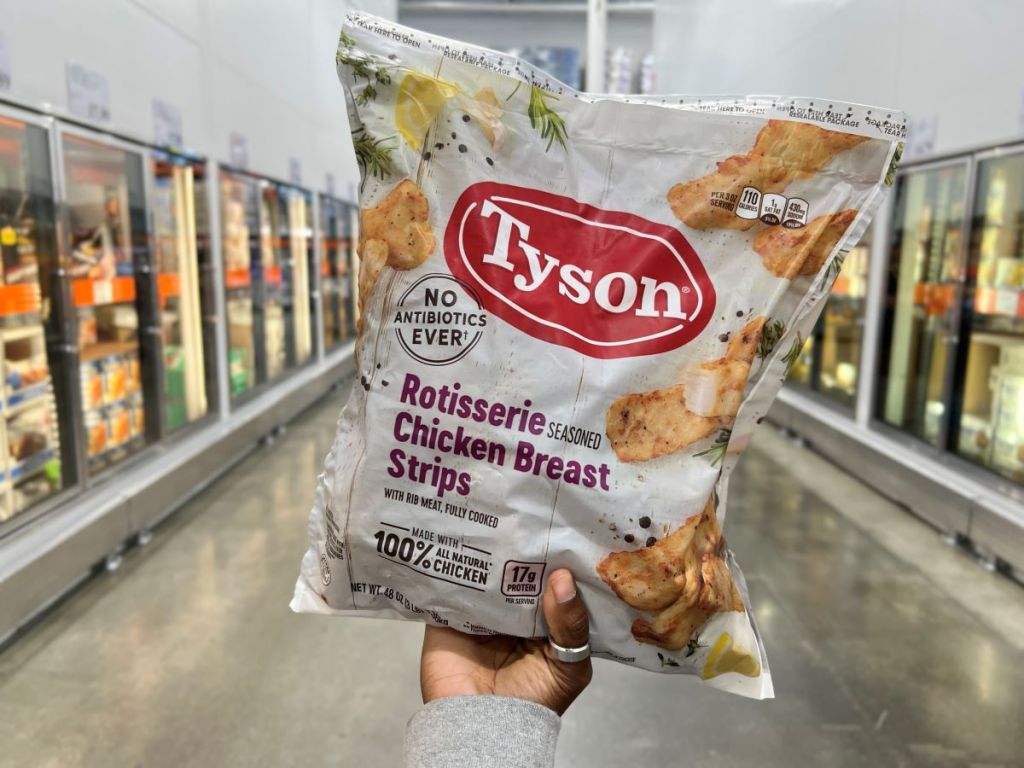 Hand holding a bag of Tyson Frozen Rotisserie Seasoned Chicken Breast Strips
