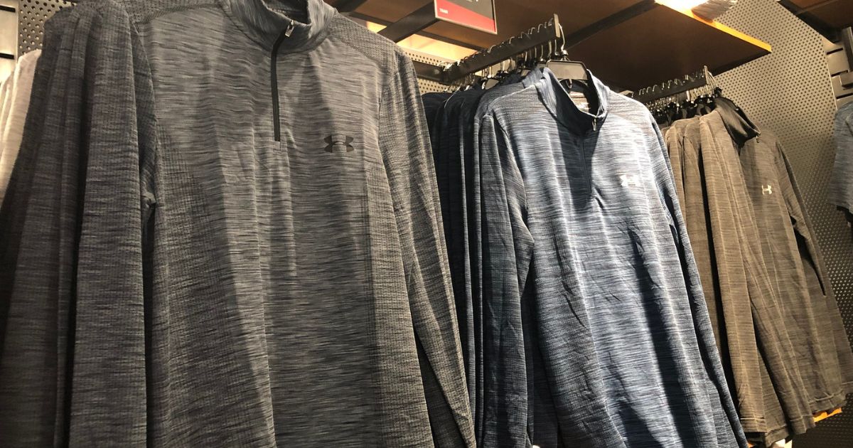 racks of Under Armour tech tops hanging at store