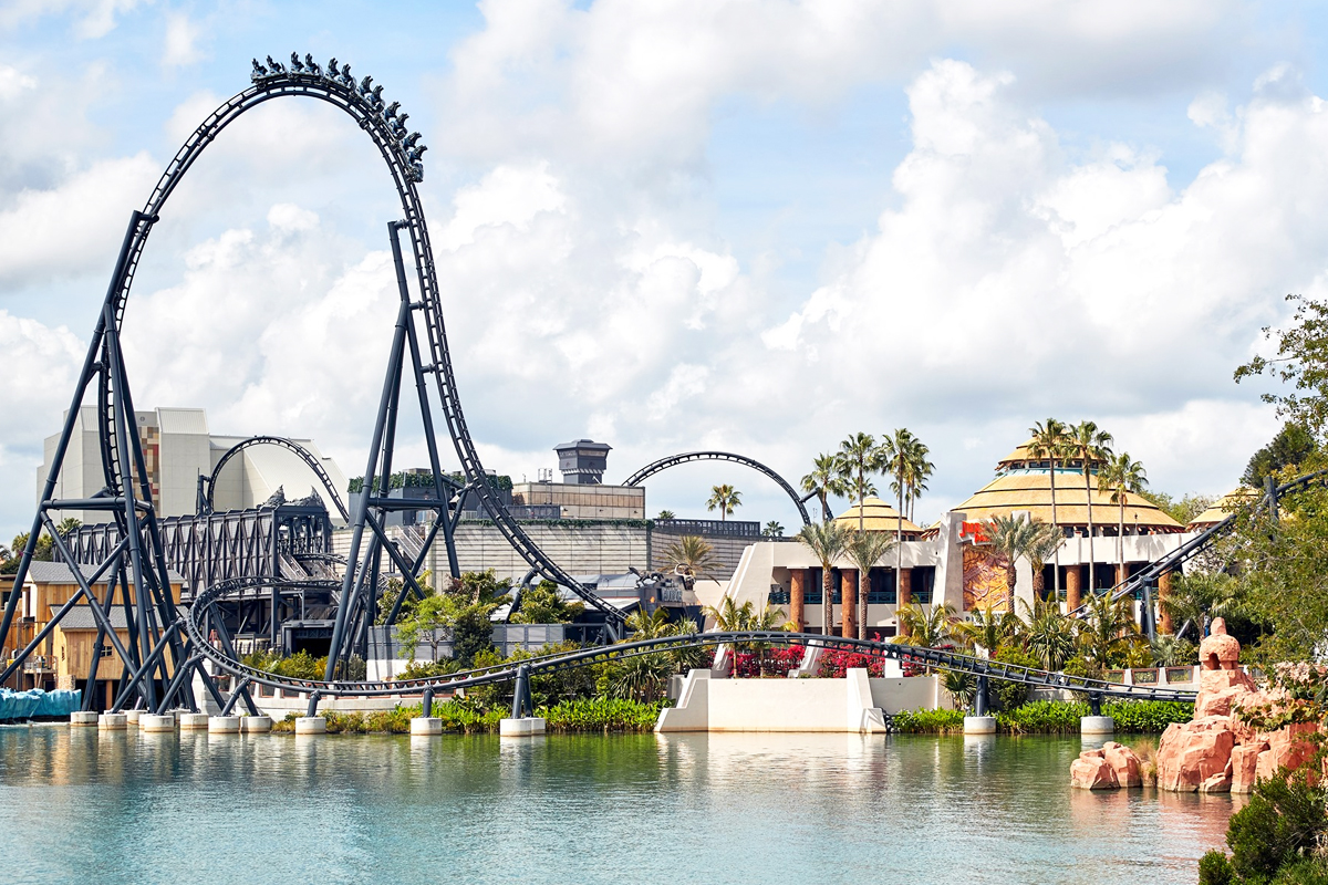 grey roller coaster on edge of theme park next to water