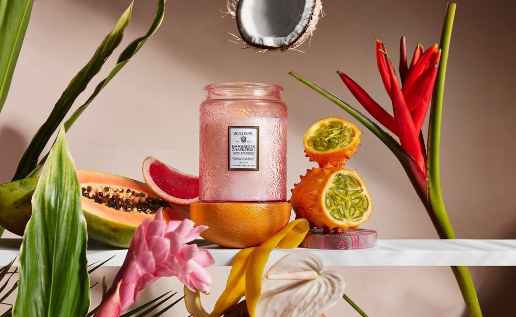 Pink candle surrounded by fruit and flowers