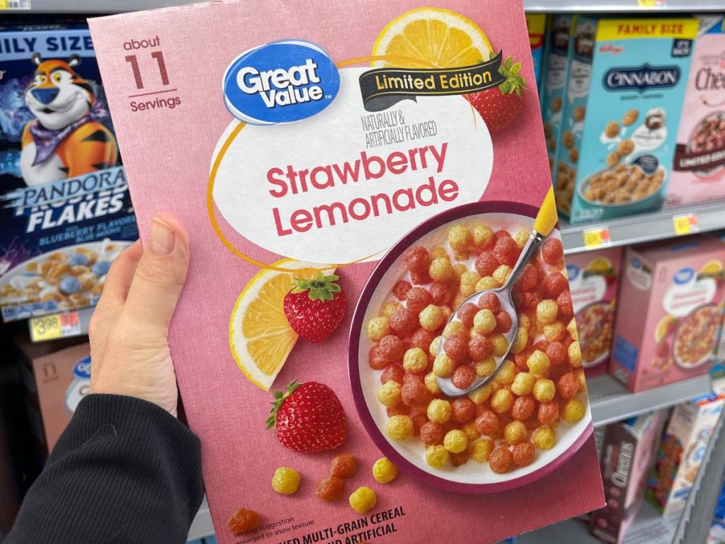 A hand holding a pink box of strawberry lemonade cereal