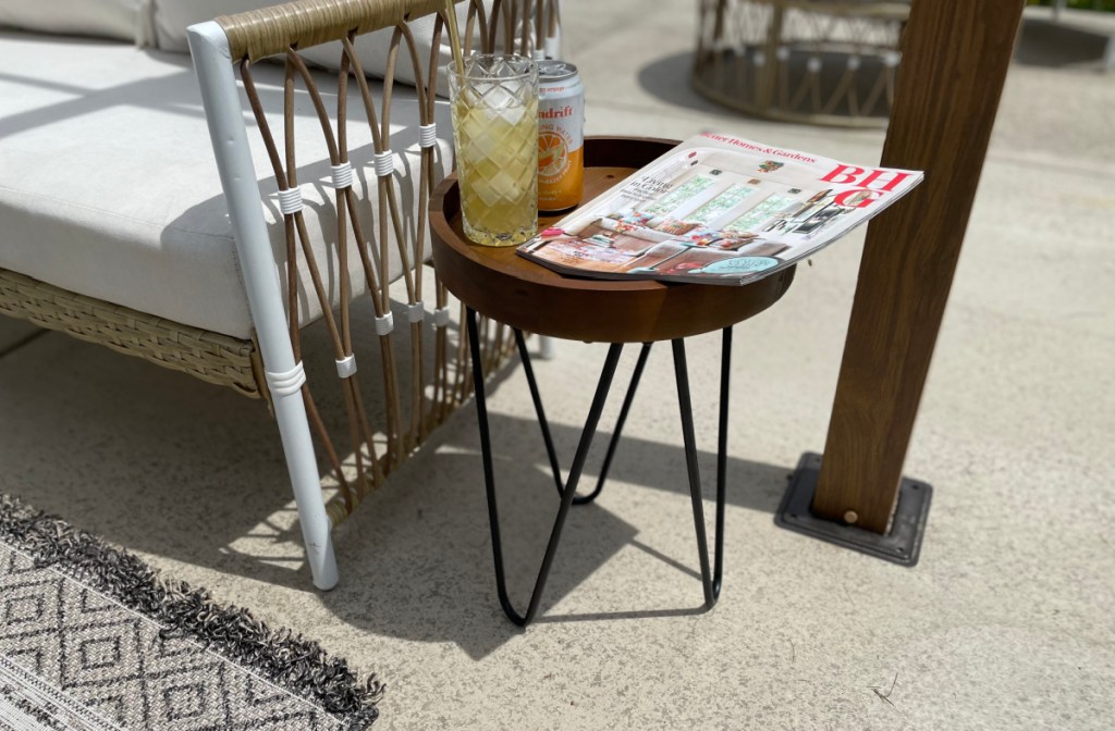 A circular wooden stand from Walmarts outdoor decor collection being used as a side table for beverages