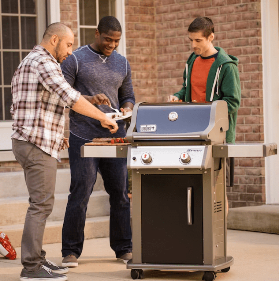 Men cooking at a Weber Spirit E210 grill