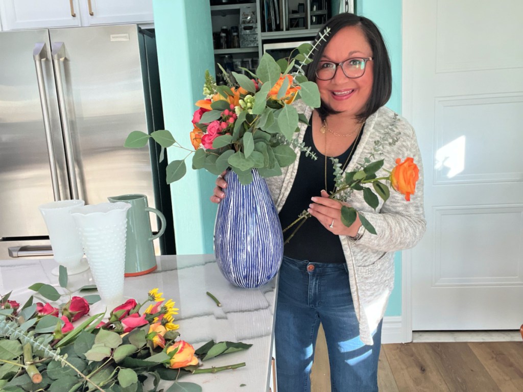 Woman assembling a bouquet at home using affordable grocery store flowers