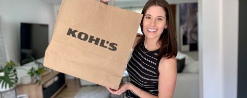 Woman holding up a large paper kohl's shopping bag