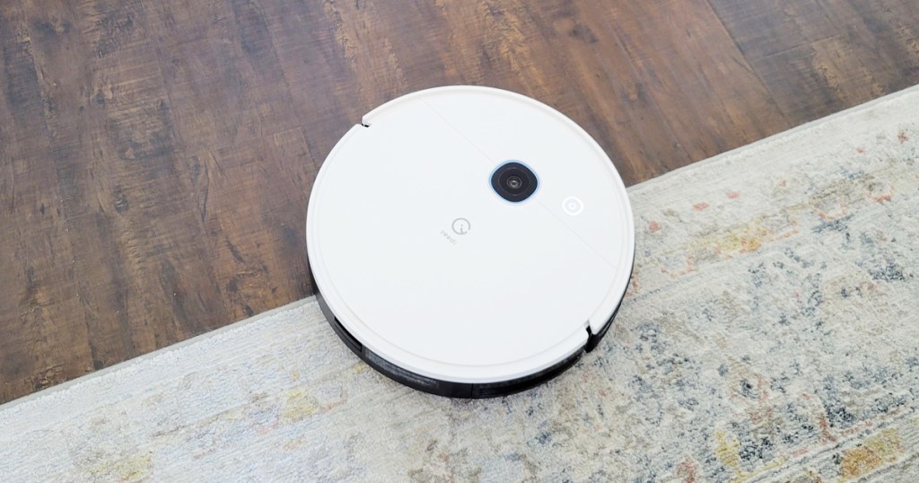 white robot vacuum on area rug and wood floor