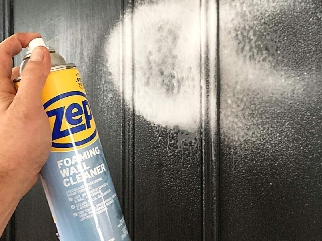 Zep foam wall cleanser spraying a black wall in persons hands
