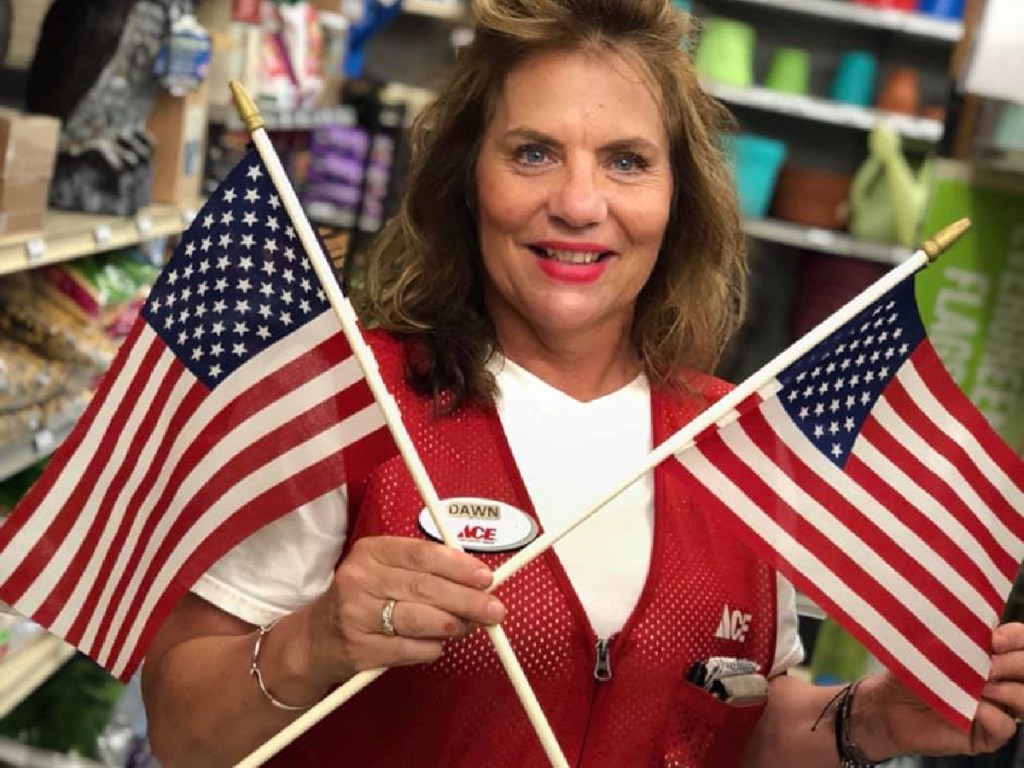 smiling ace hardware employee holding two american flags