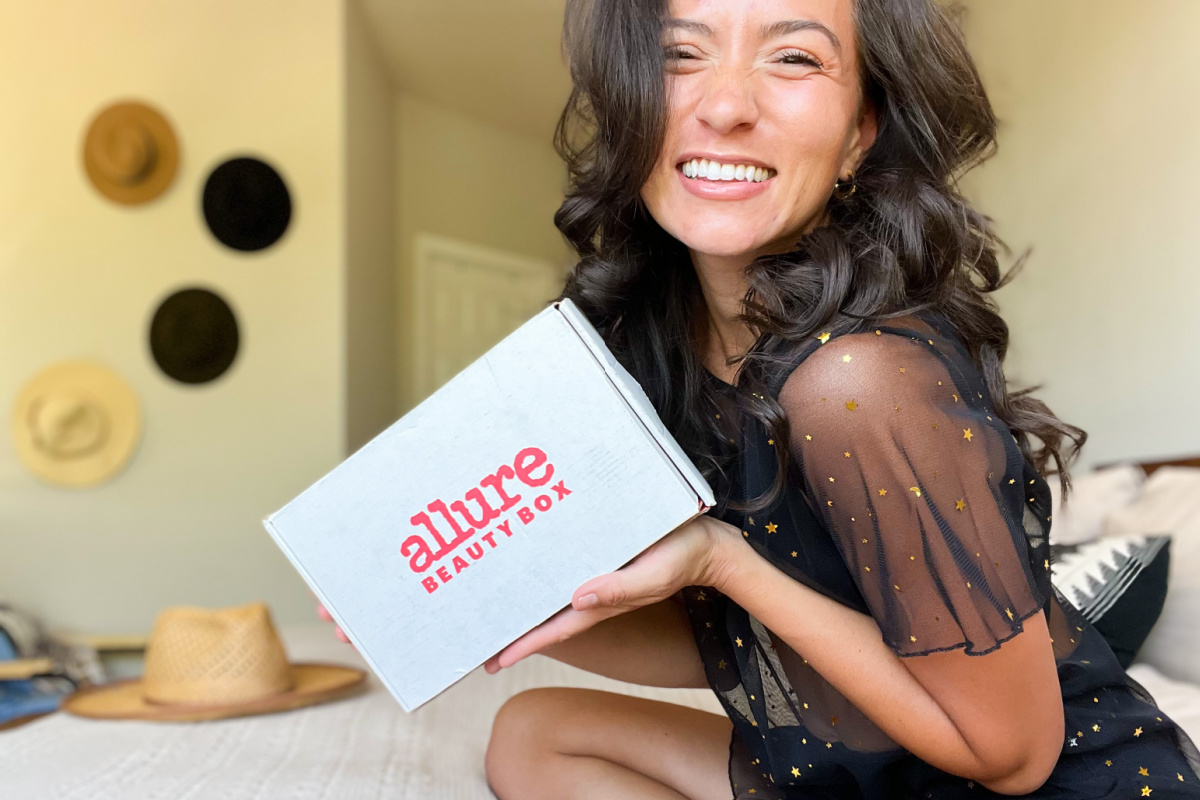 woman sitting on bed holding allure beauty box