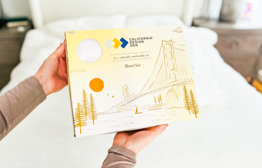 hands holding california design den box of bed sheets
