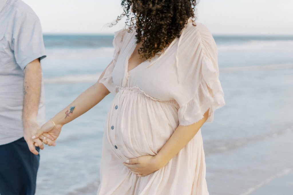 pregnant woman holding hand at beach