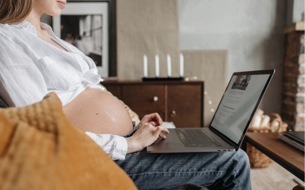 pregnant woman typing on laptop