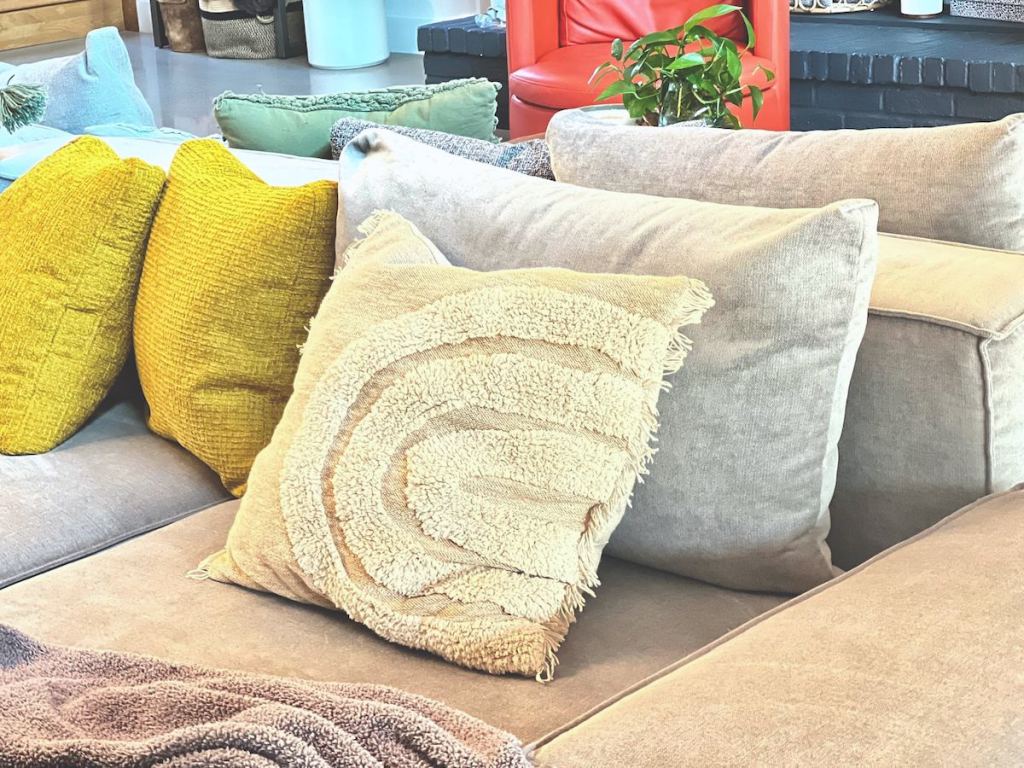 neutral pillow with arches on gray sectional couch with bright yellow pillows