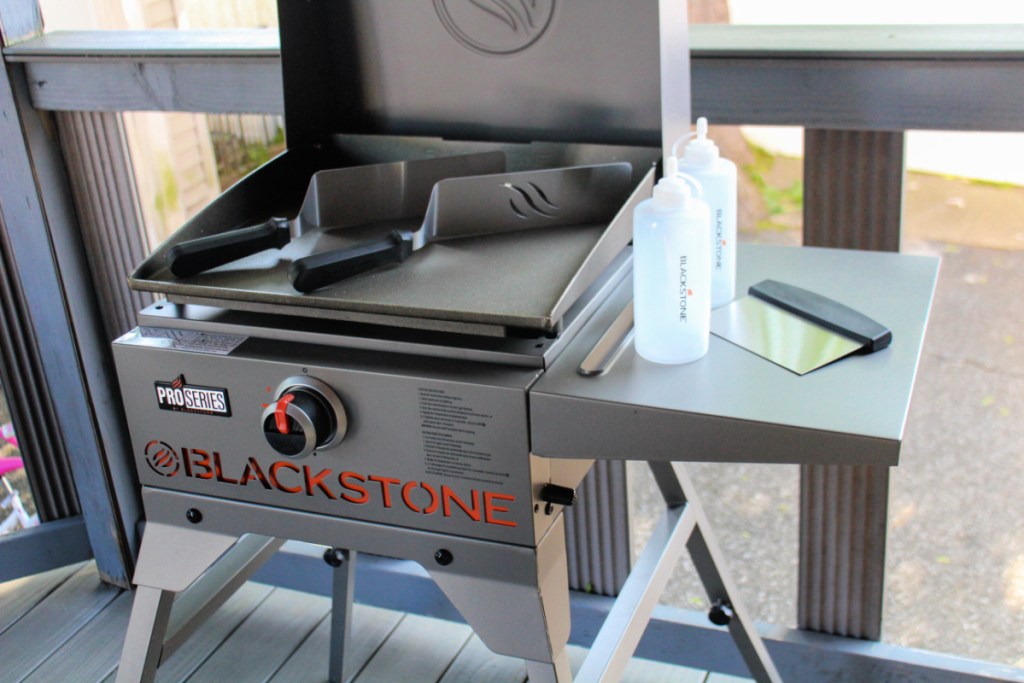 assembled blackstone griddle with open cover and accessories set out