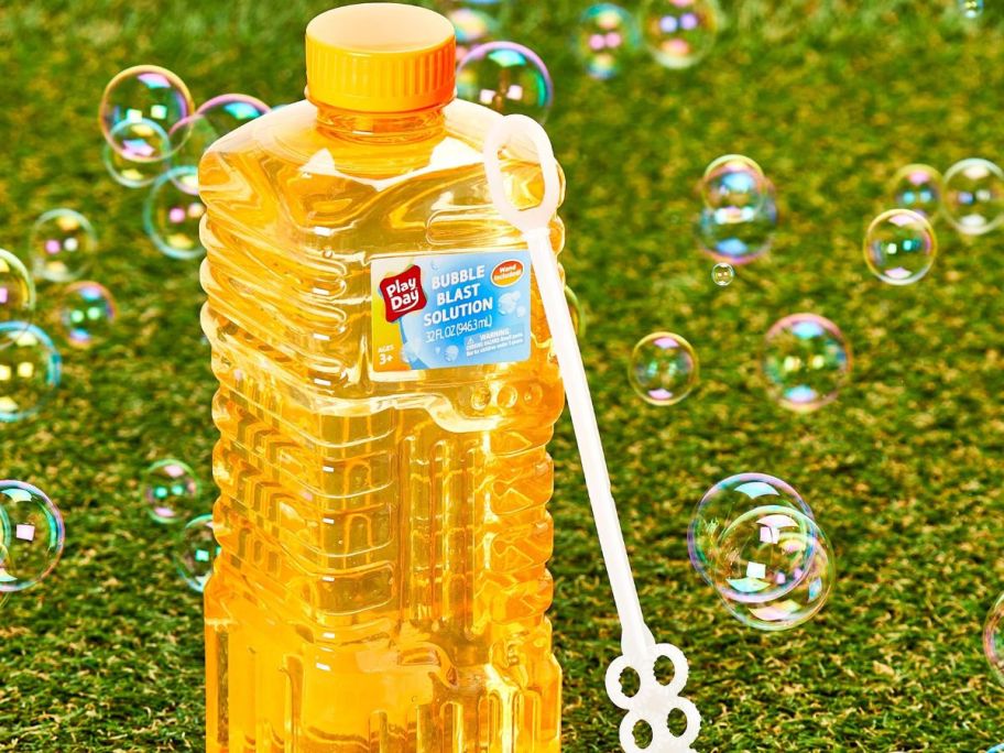 Play Day Bubble Blast Solution, 32 fl oz Bottle, Orange with bubbles floating around on grass
