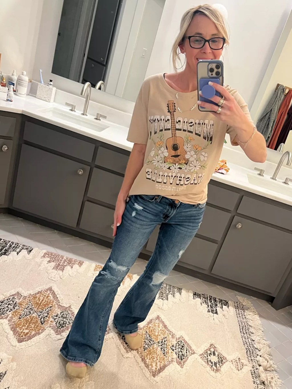 woman taking selfie in mirror wearing graphic tee shirt