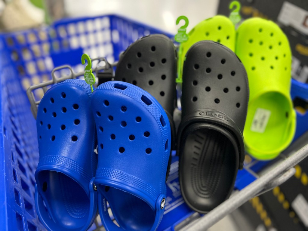 three colorful pairs of croc shoes in a shopping cart basket