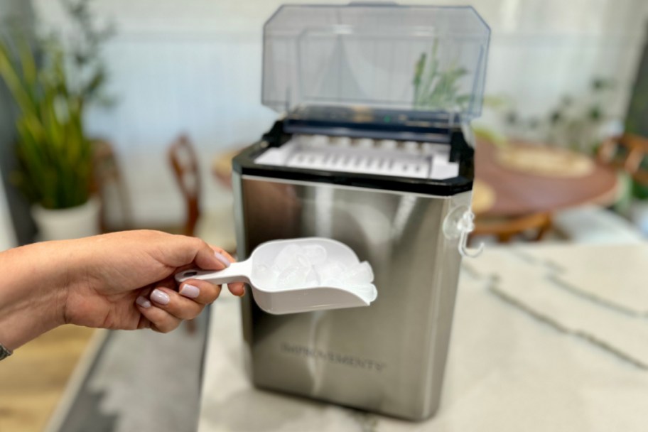 hand holding ice scoop in front of ice maker