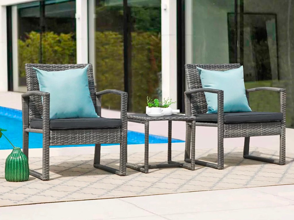 gray patio set with teal pillows next to pool