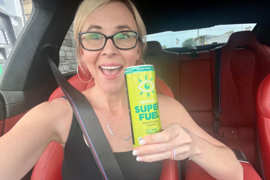 woman holding energy drink can in hand in car