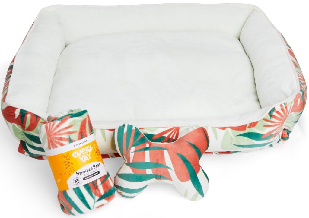 white dog bed with floral lining with blanket and toy