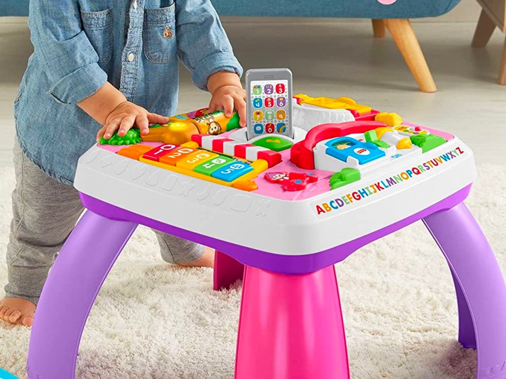 child playing with fisher price pink and purple learning table